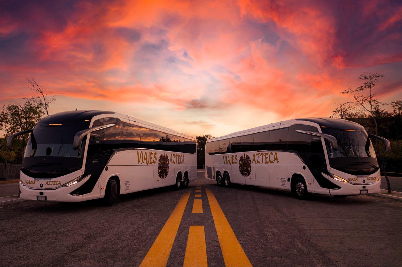 Dos autobuses de Viajes Azteca bajo un cielo al atardecer