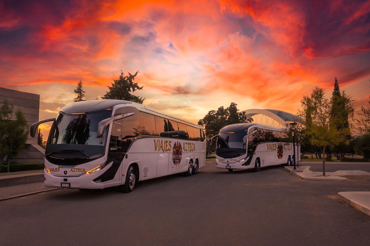 Autobuses de Viajes Azteca en una avenida arbolada
